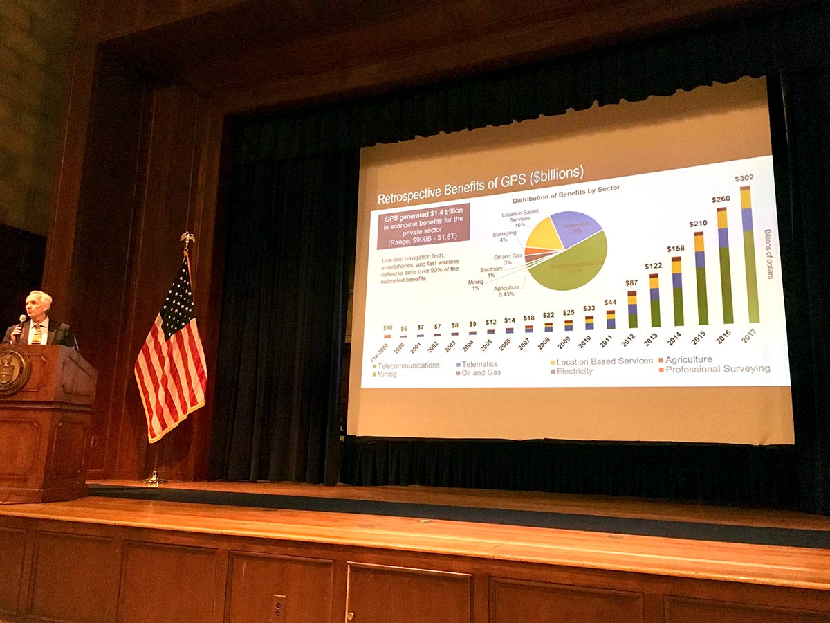 Michael Gallaher of RTI International speaking at podium with analytical graph on screen