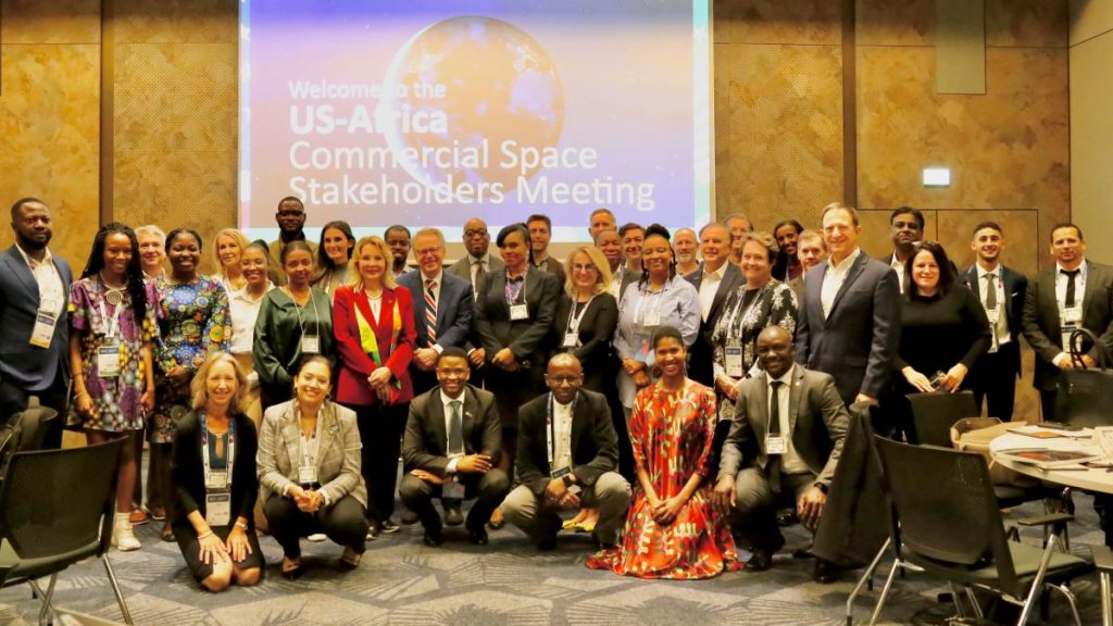 Group shot of men and women standing in front of screen reading "Welcome to the US-Africa Commercial Space Stakeholders Meeting"