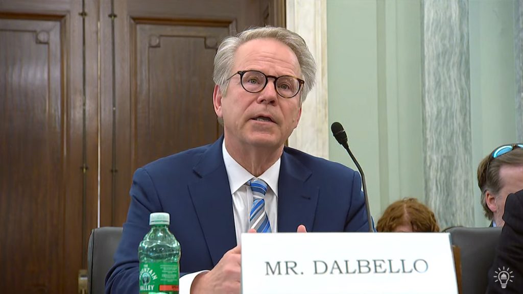 OSC Director Richard DalBello speaks into a microphone with a nameplate reading "Mr. DalBello"