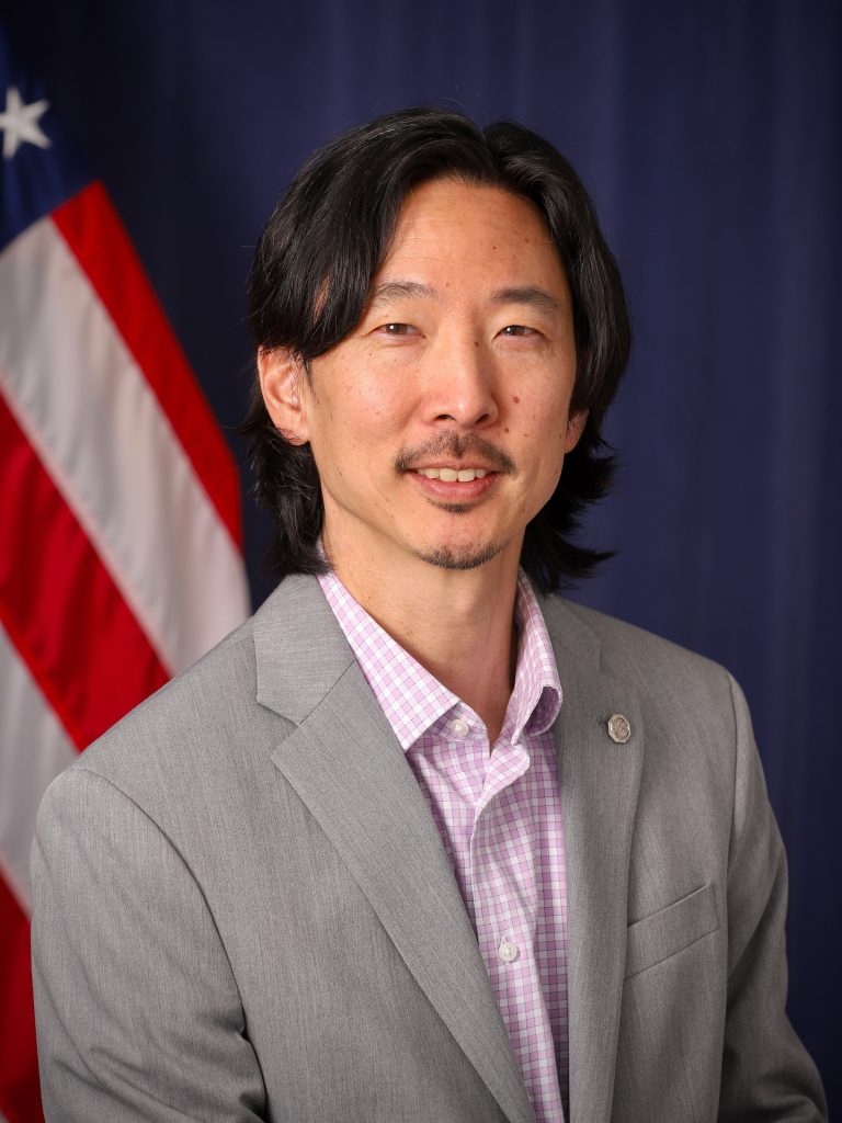 Headshot of Jason Y. Kim with U.S. flag in background